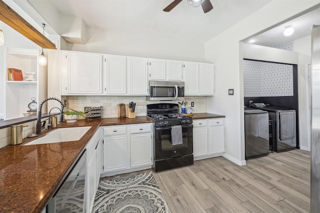 kitchen with washing machine and dryer, light wood-type flooring, stainless steel appliances, white cabinetry, and a sink