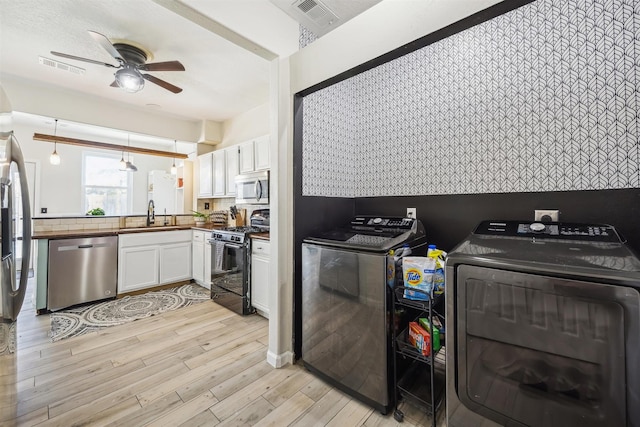 kitchen with visible vents, washer and clothes dryer, light wood-style flooring, white cabinets, and stainless steel appliances