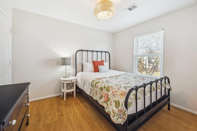 bedroom with visible vents, baseboards, and wood finished floors