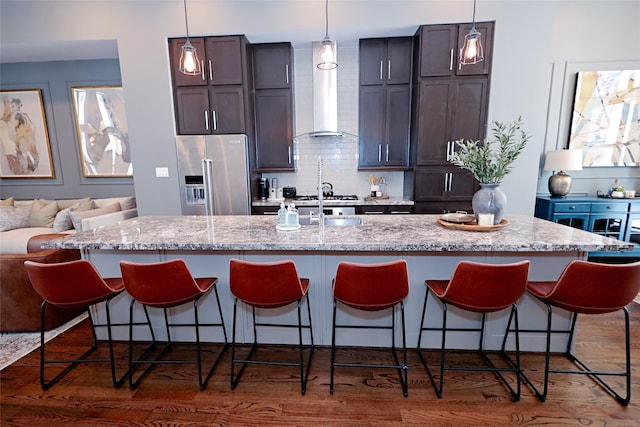 kitchen featuring a large island, a breakfast bar, tasteful backsplash, dark wood-style floors, and stainless steel appliances