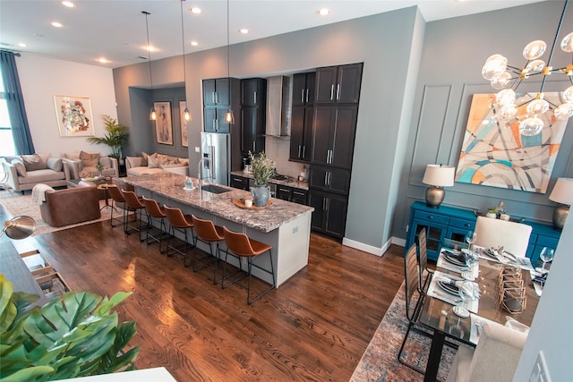 kitchen featuring light stone counters, high end fridge, a kitchen breakfast bar, and dark wood-style flooring