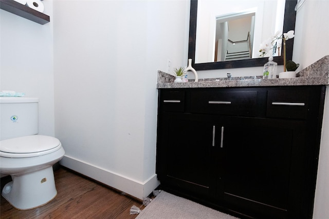 bathroom featuring toilet, vanity, baseboards, and wood finished floors