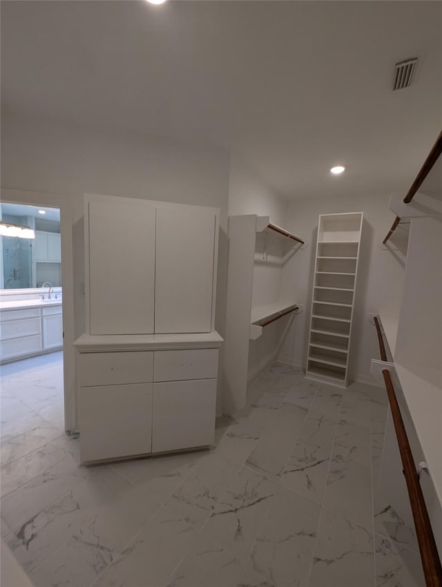 walk in closet with visible vents, marble finish floor, and a sink