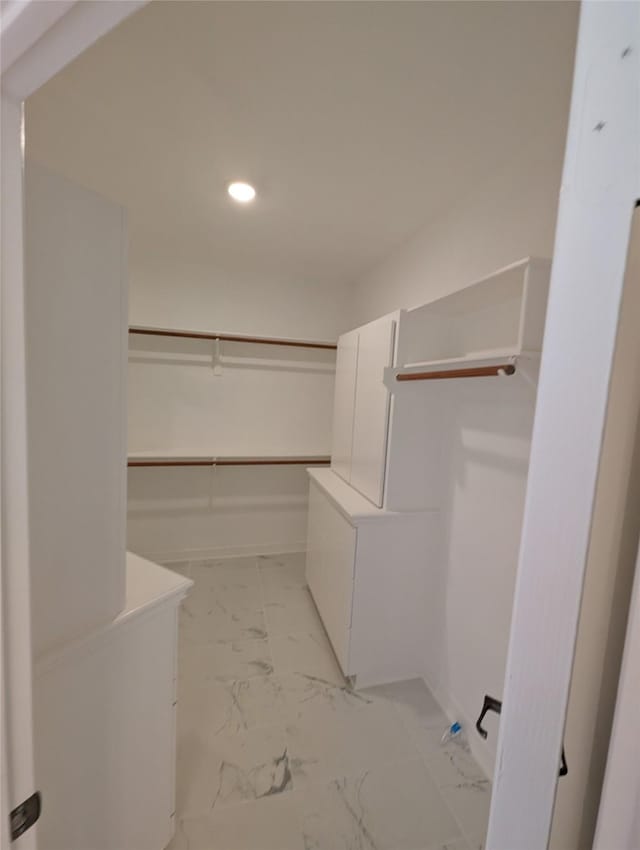 walk in closet featuring marble finish floor