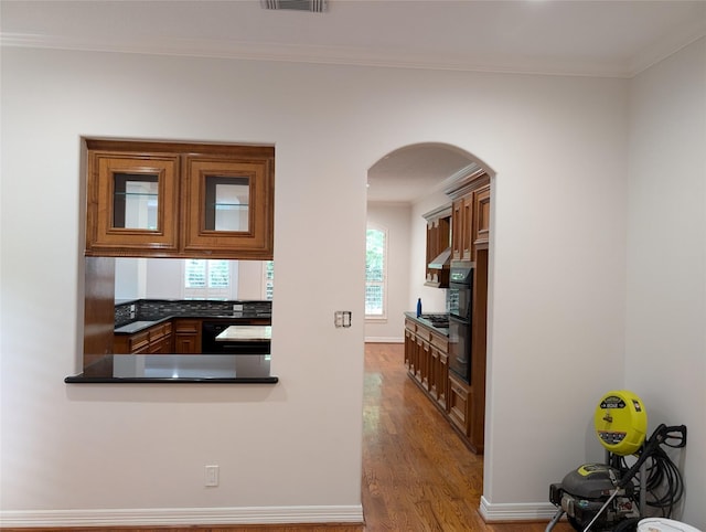 kitchen with dark countertops, visible vents, black dishwasher, ornamental molding, and wood finished floors