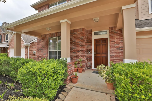 view of exterior entry featuring a porch and brick siding