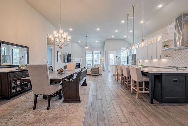 dining area with recessed lighting, ceiling fan with notable chandelier, high vaulted ceiling, and light wood-type flooring