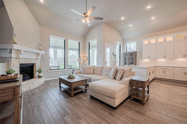 living room featuring plenty of natural light, light wood-type flooring, ceiling fan, and vaulted ceiling