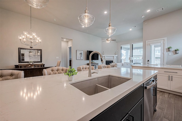 kitchen featuring open floor plan, ceiling fan with notable chandelier, wood finished floors, and a sink