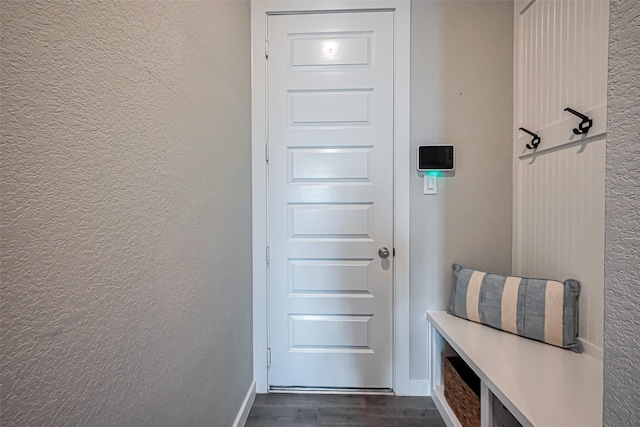 mudroom with baseboards, dark wood-type flooring, and a textured wall