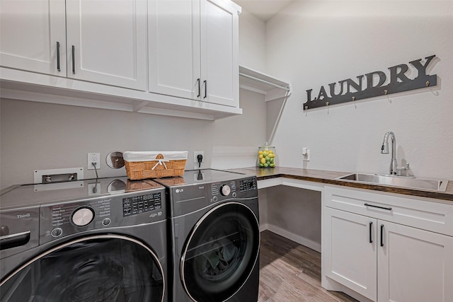 clothes washing area featuring washing machine and clothes dryer, cabinet space, light wood-style floors, and a sink