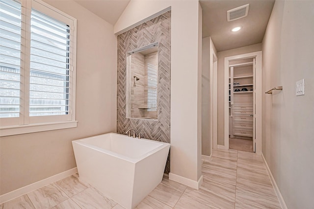 full bathroom featuring baseboards, visible vents, tiled shower, a freestanding tub, and a walk in closet