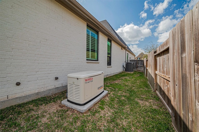 view of home's exterior with cooling unit, a fenced backyard, brick siding, and a yard