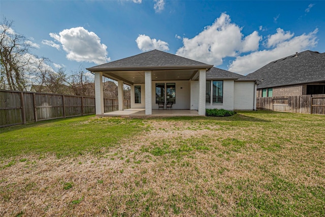 back of property with brick siding, a patio area, a fenced backyard, and a lawn