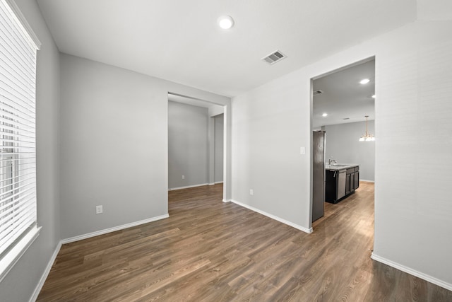 spare room with baseboards, visible vents, dark wood-style flooring, a sink, and a chandelier