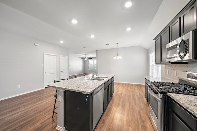 kitchen featuring a sink, appliances with stainless steel finishes, wood finished floors, plenty of natural light, and a kitchen island with sink