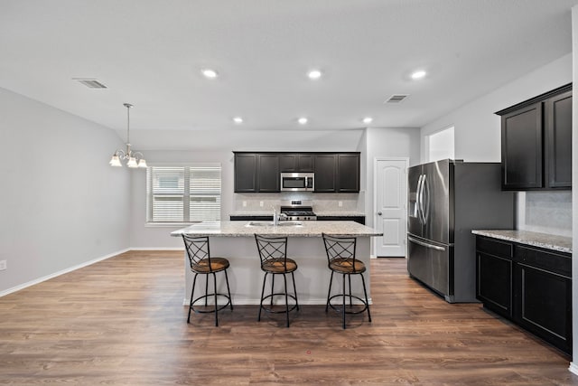 kitchen featuring visible vents, a sink, tasteful backsplash, stainless steel appliances, and dark wood-style flooring