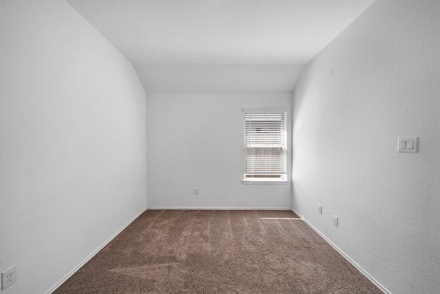 carpeted spare room featuring baseboards and lofted ceiling