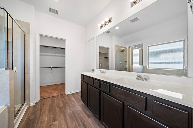 full bathroom featuring a shower stall, a spacious closet, visible vents, and a sink