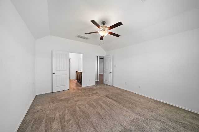 unfurnished bedroom featuring visible vents, lofted ceiling, ensuite bathroom, carpet floors, and baseboards