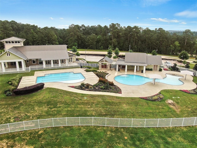 pool featuring a patio, a lawn, fence, and a view of trees