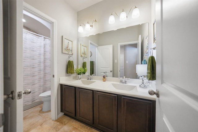 bathroom featuring double vanity, toilet, and a sink