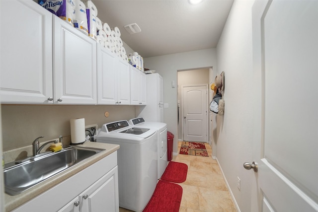 clothes washing area featuring a sink, cabinet space, baseboards, and washer and clothes dryer