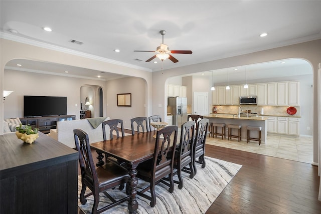 dining space featuring visible vents, recessed lighting, arched walkways, light wood-style floors, and crown molding