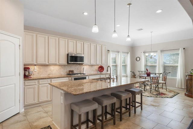 kitchen with stainless steel microwave, visible vents, light stone countertops, decorative backsplash, and a sink