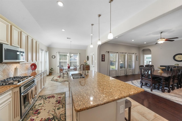 kitchen with decorative backsplash, cream cabinets, stainless steel appliances, and a sink