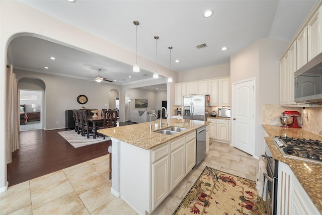 kitchen featuring visible vents, a sink, open floor plan, stainless steel appliances, and decorative backsplash