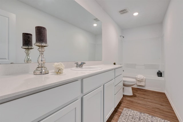 bathroom featuring visible vents, a washtub, toilet, wood finished floors, and vanity