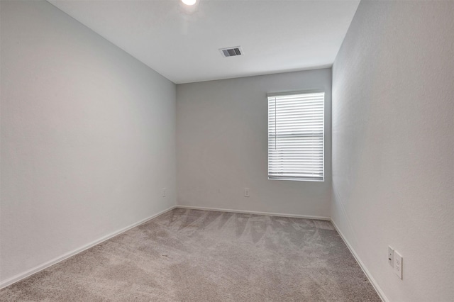 spare room featuring baseboards, visible vents, and light carpet