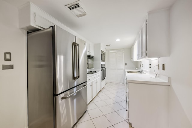 kitchen featuring visible vents, a sink, freestanding refrigerator, wall oven, and light tile patterned floors