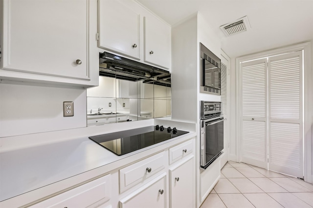 kitchen featuring visible vents, light countertops, light tile patterned flooring, white cabinets, and black appliances