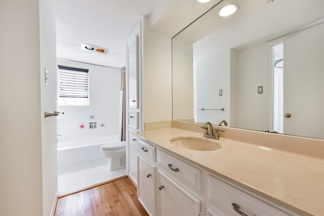 bathroom featuring toilet, shower / washtub combination, wood finished floors, and vanity