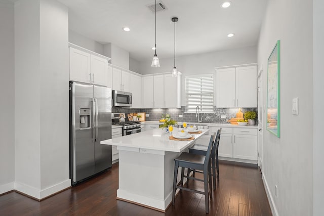 kitchen featuring visible vents, dark wood-type flooring, decorative backsplash, appliances with stainless steel finishes, and white cabinetry