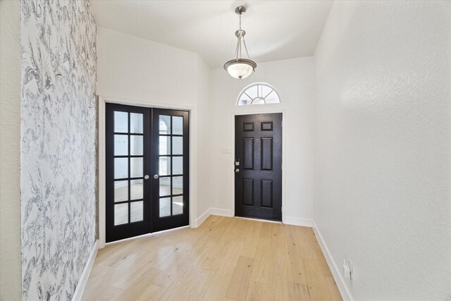 foyer with wood finished floors, french doors, and baseboards