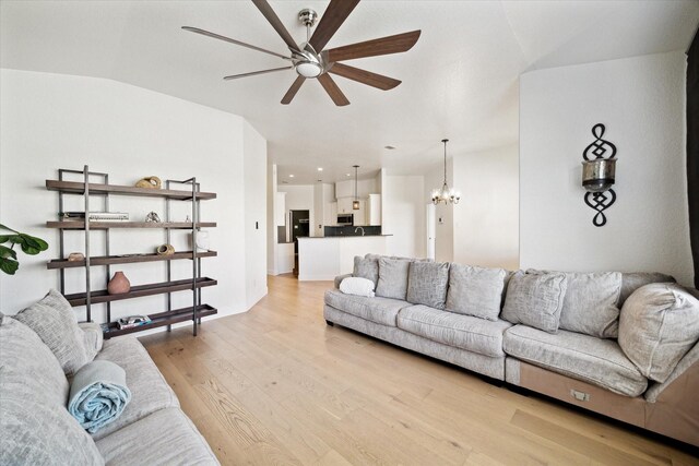 living room with light wood-style flooring, vaulted ceiling, and ceiling fan with notable chandelier