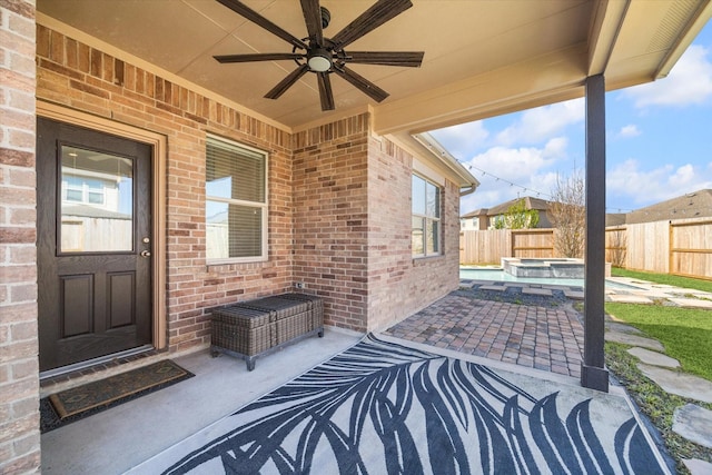 view of patio / terrace with a ceiling fan, fence, and a pool with connected hot tub