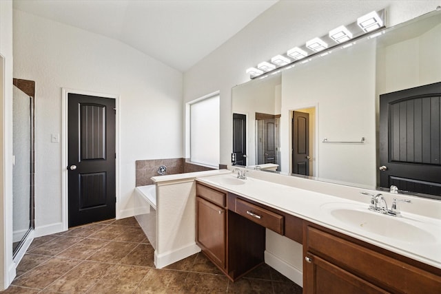 bathroom featuring vaulted ceiling, a shower stall, a garden tub, and a sink