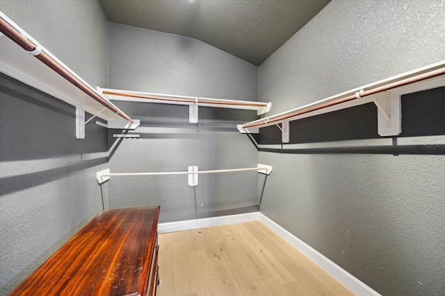 spacious closet with lofted ceiling and wood finished floors