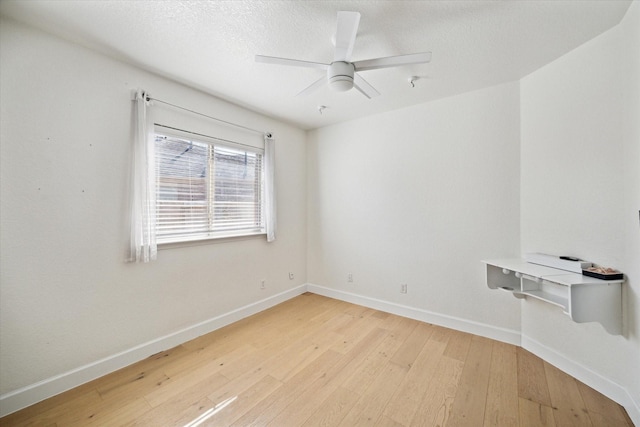 spare room featuring light wood-style flooring, a ceiling fan, baseboards, and a textured ceiling