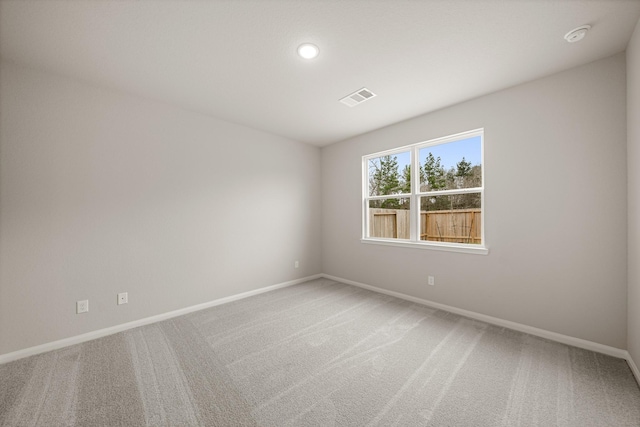 empty room featuring visible vents, light carpet, and baseboards