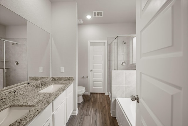 full bathroom featuring visible vents, toilet, a stall shower, a sink, and wood finished floors