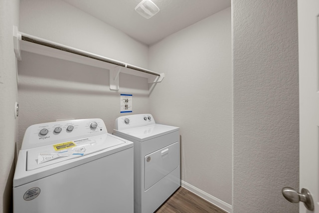 clothes washing area featuring dark wood finished floors, laundry area, separate washer and dryer, and baseboards