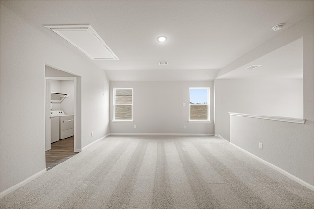 unfurnished room featuring carpet, visible vents, attic access, plenty of natural light, and washing machine and dryer