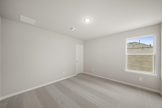 unfurnished room with visible vents, light carpet, and baseboards