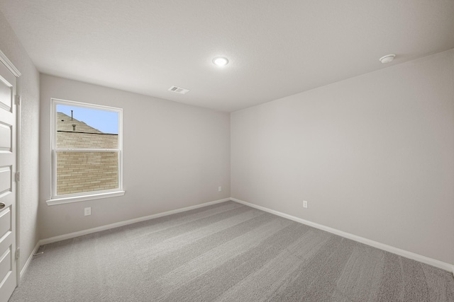 carpeted spare room with visible vents and baseboards