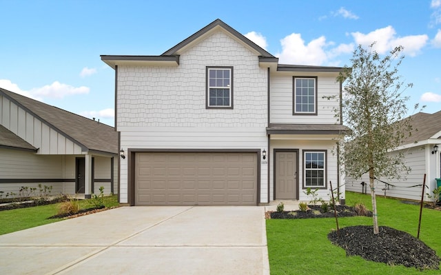 traditional home with an attached garage, concrete driveway, and a front yard